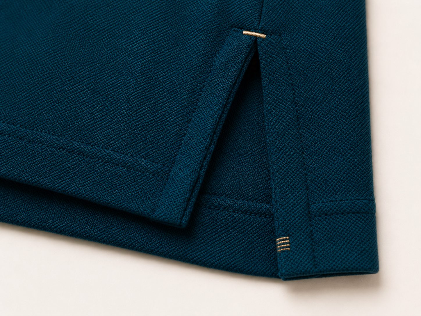 Close-up of the side hem vent showing layered construction with a brass bartack and clean-finished seam edges
